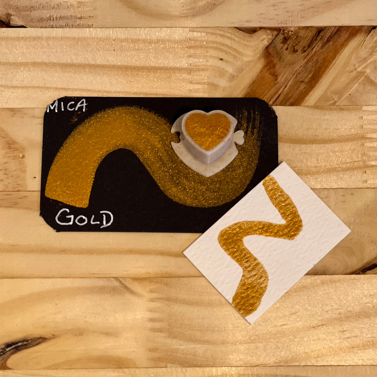  gold mica shimmer watercolor paint  heart shape paint pan with swatch on on a black card with 'Mica Gold' text and small swatch on white paper
