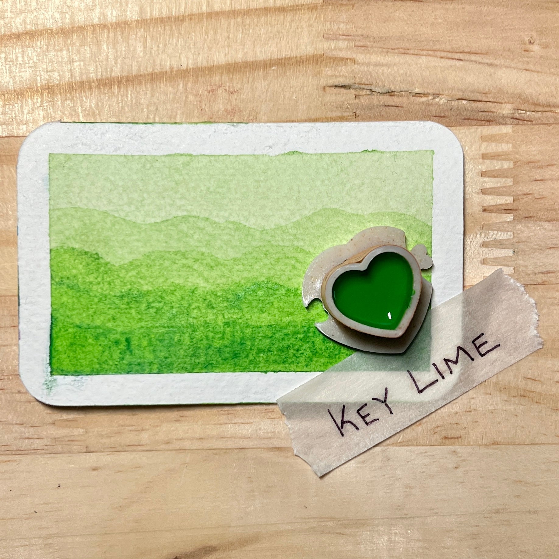 bright lime green watercolor gradient landscape, heart-shape watercolor pan, labeled 'Key Lime', on a wooden surface.