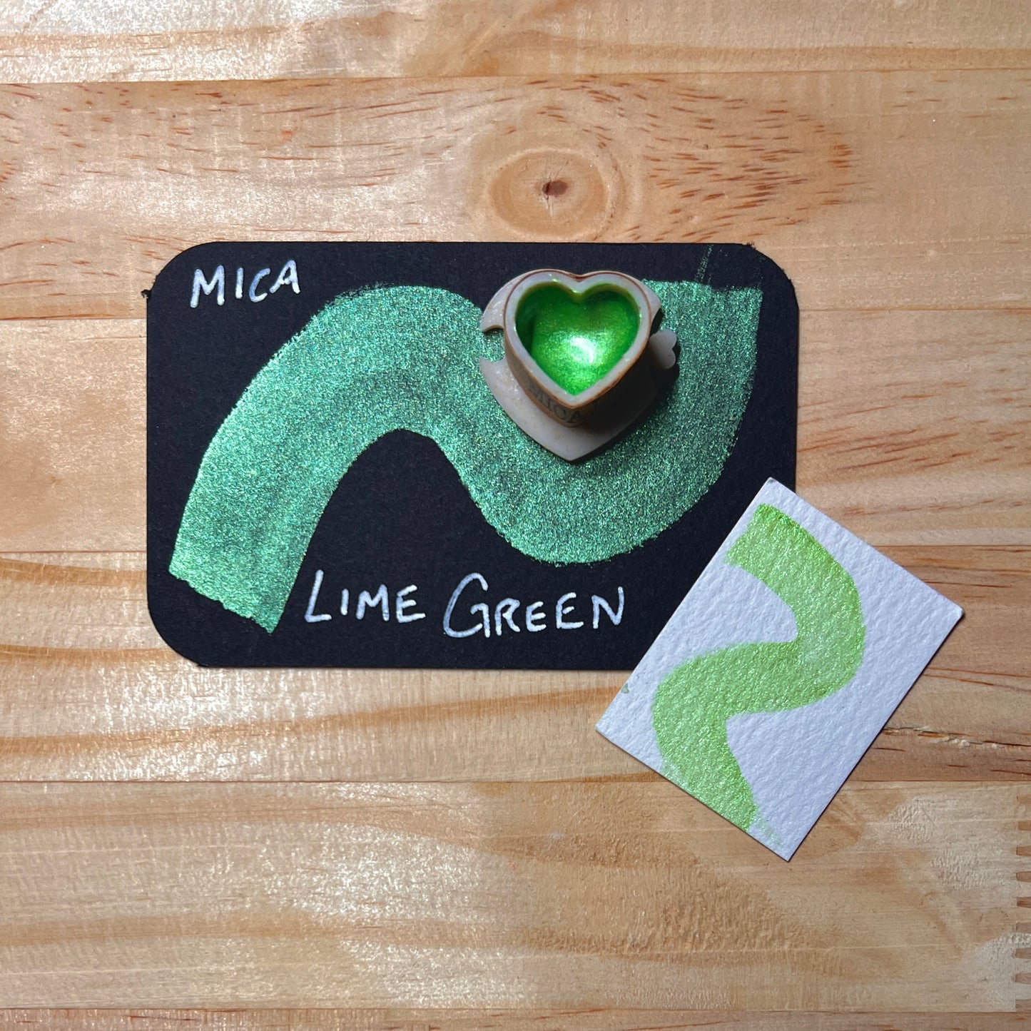 lime green mica shimmer watercolor paint  heart shape paint pan with swatch on on a black card with 'Mica Lime green' text and small swatch on white paper