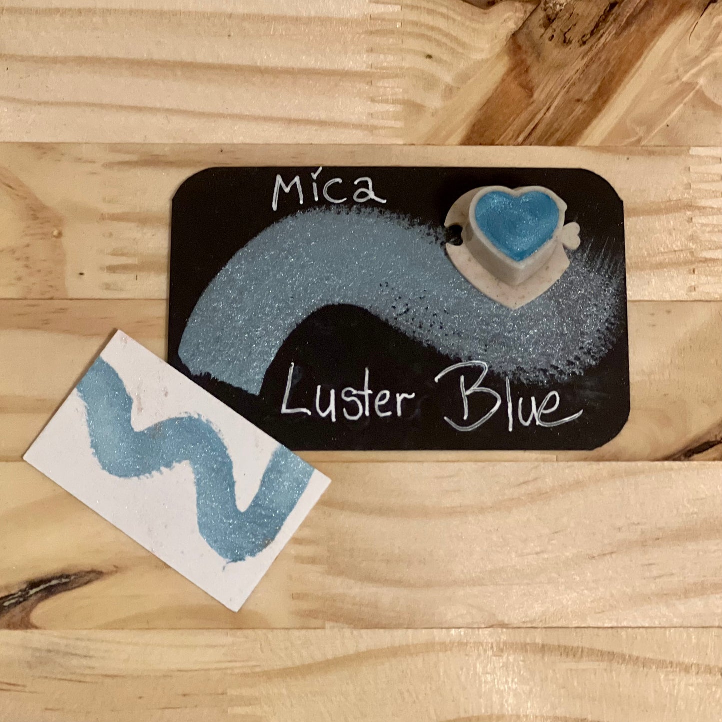 Mica Luster Blue color sample on a wooden surface with a black card displaying the color name.