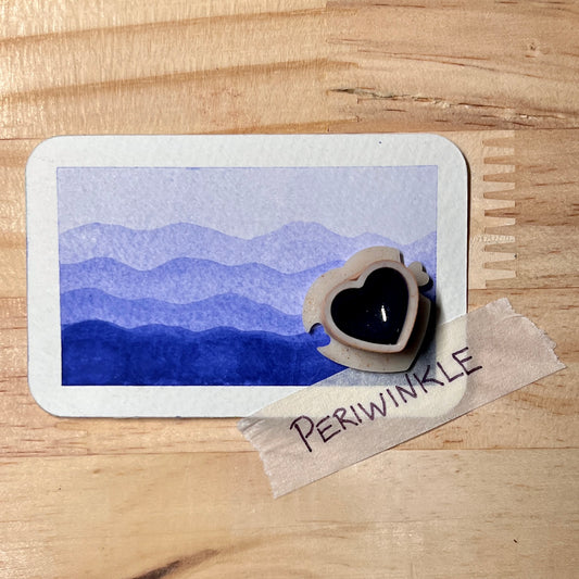 blue purple watercolor gradient landscape, heart-shape watercolor pan, labeled 'periwinkle', on a wooden surface.