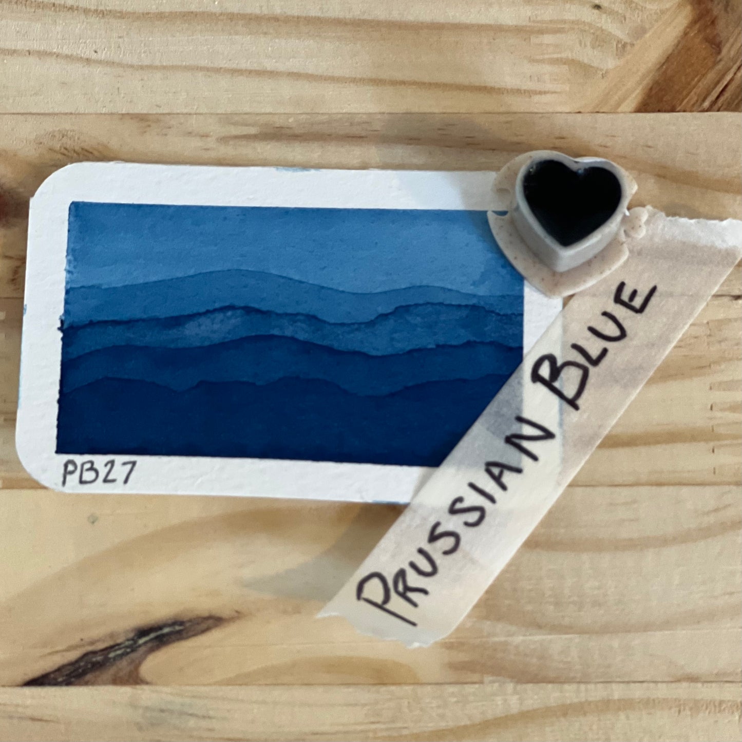 single heart shaped half pan of watercolor paint showing the product name and a swatch of prussian blue paint.