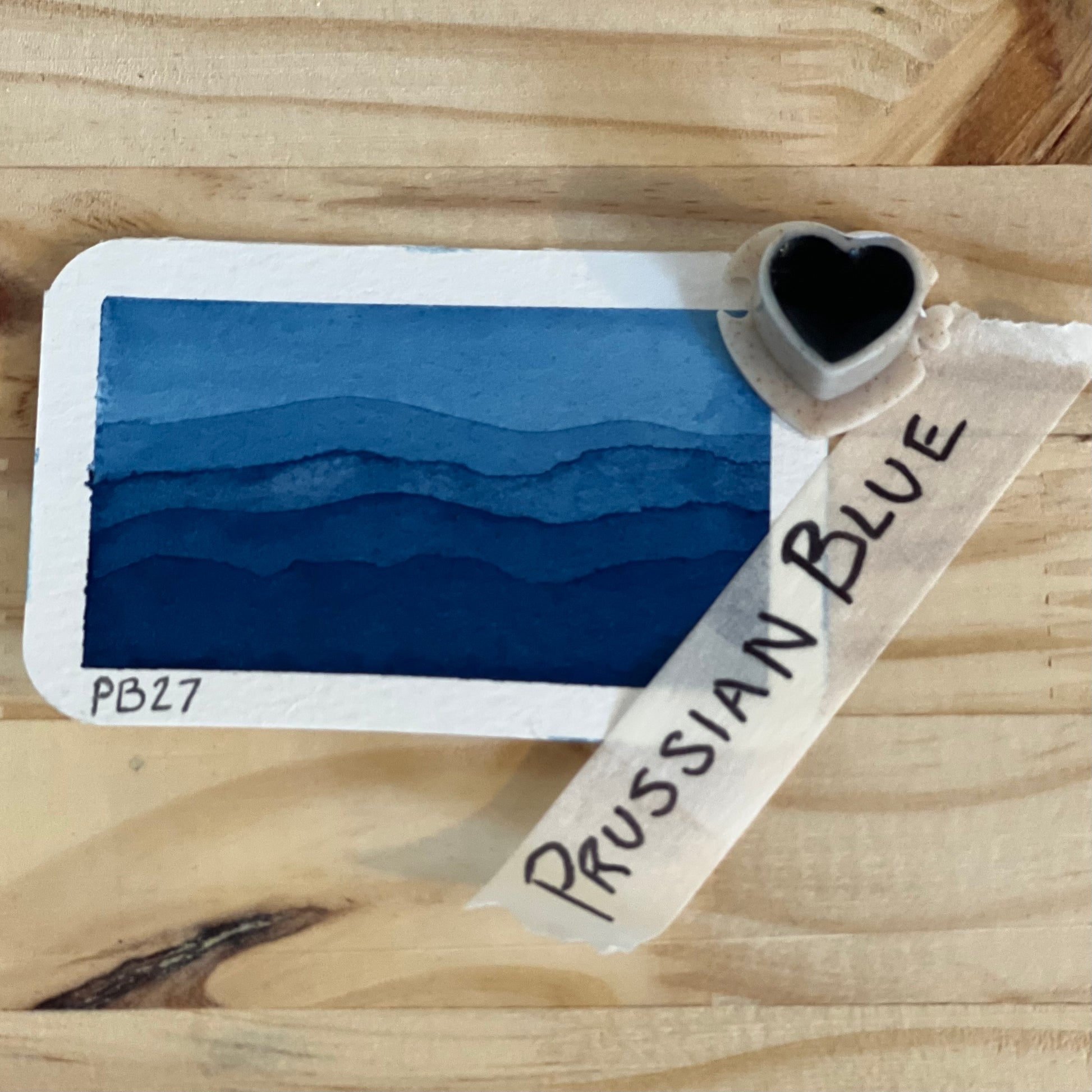 single heart shaped half pan of watercolor paint showing the product name and a swatch of prussian blue paint.