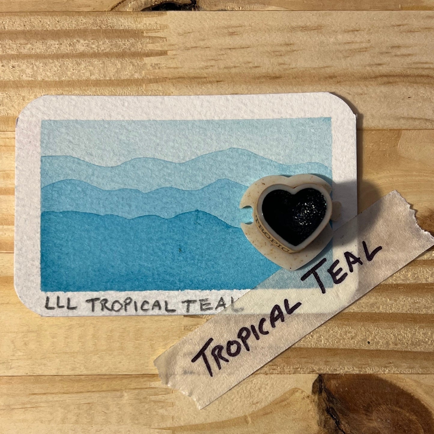 Color swatch labeled 'Tropical Teal' on a wooden surface